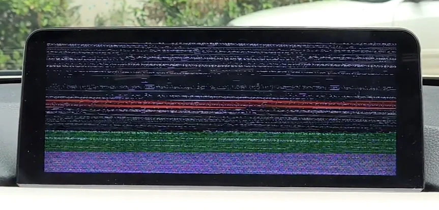 Malfunctioning car screen displaying static and distorted colors.